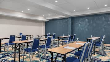 A conference room with tables and chairs, a patterned carpet, and a blue accent wall.