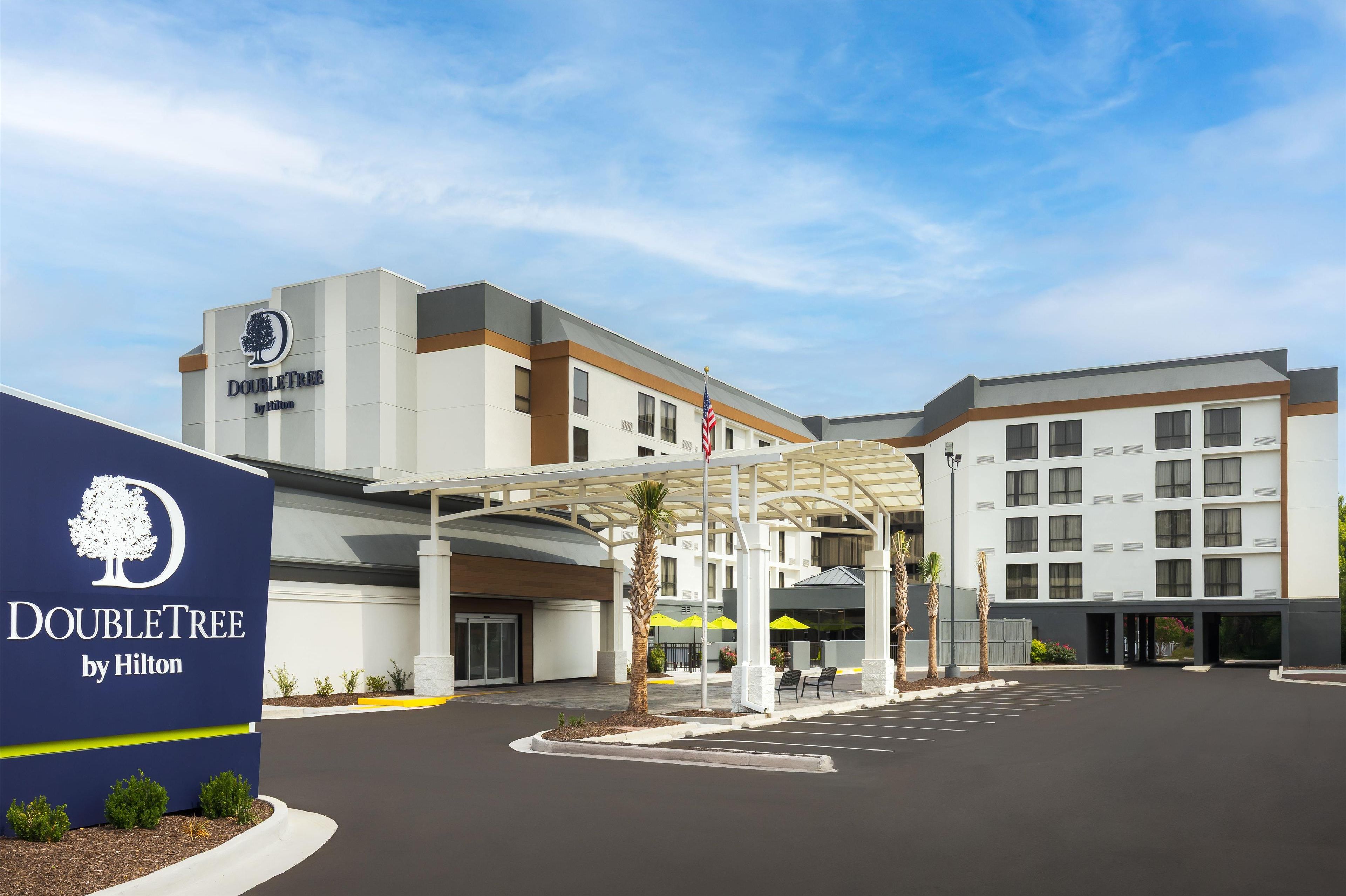 A DoubleTree by Hilton hotel with a modern design, a covered entrance, and a parking lot.