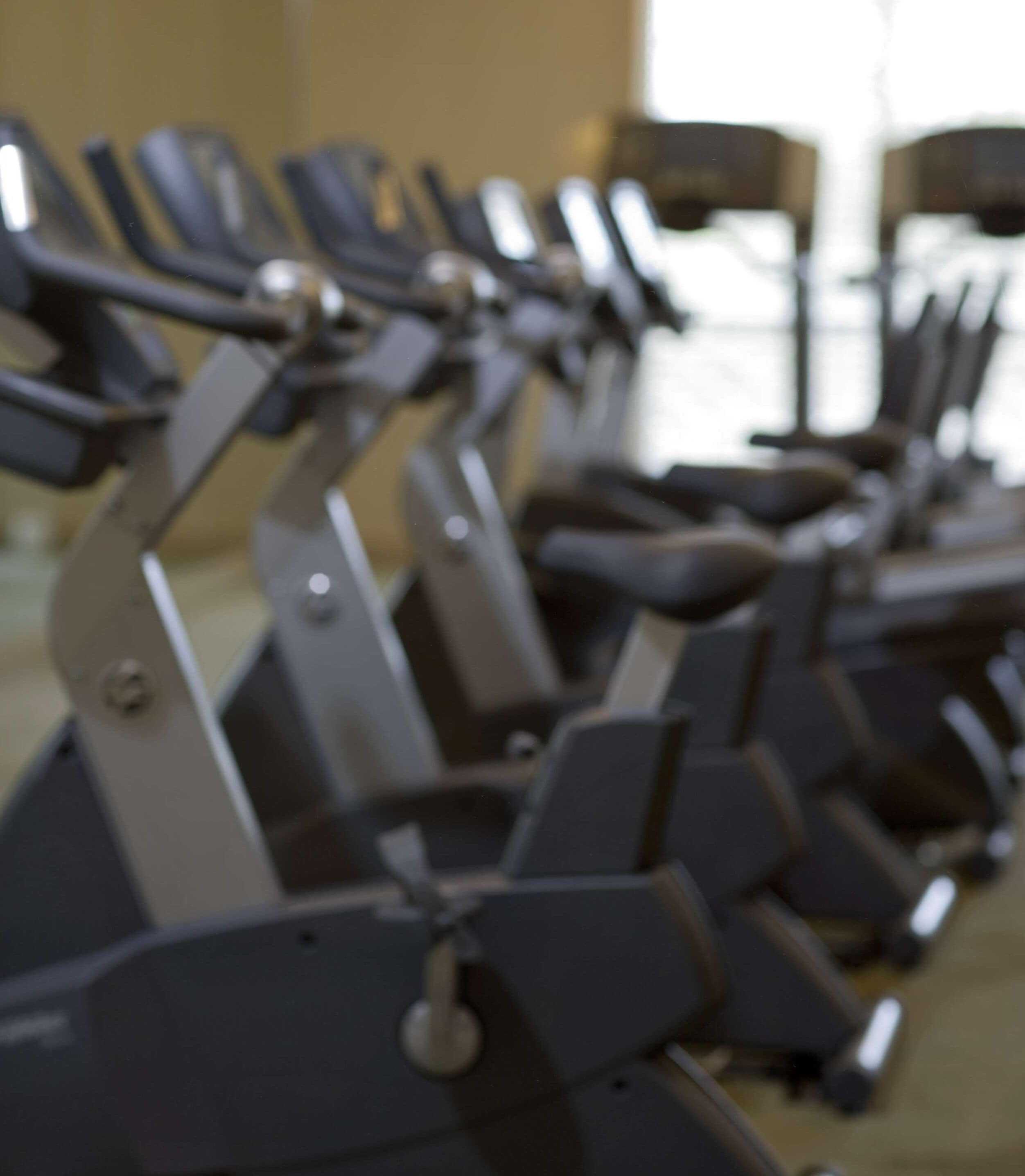 Une rangée de vélos d’appartement alignés dans une salle de sport.
