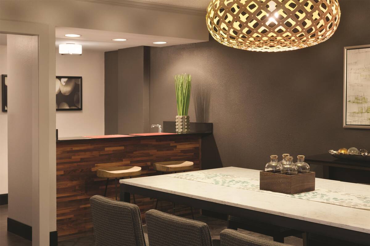 A modern dining area with a long table, chairs, and a decorative centerpiece.