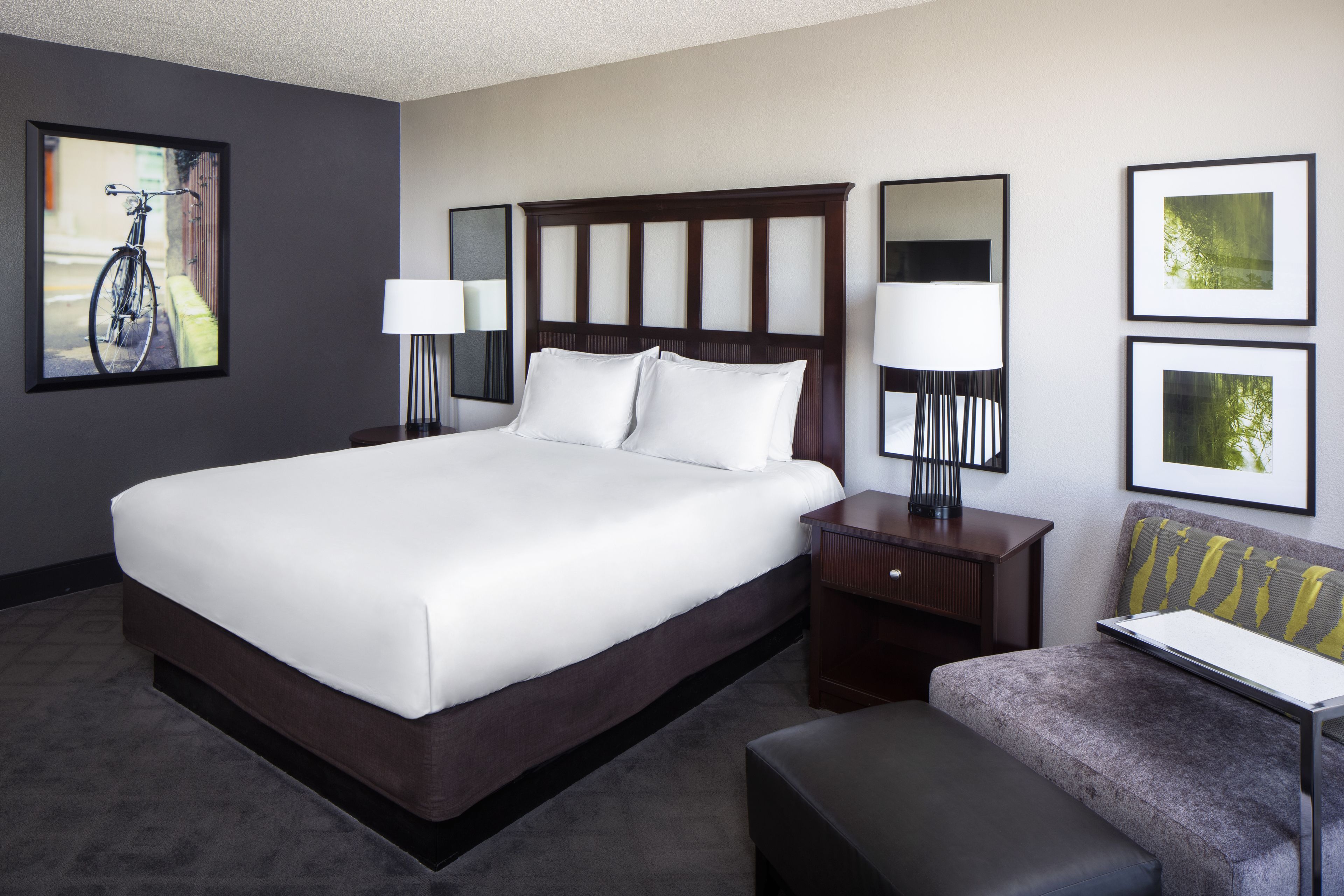 Quarto de hotel com cama grande, mesas de cabeceira, escrivaninha e uma cadeira.