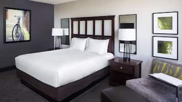 Quarto de hotel com cama grande, mesas de cabeceira, escrivaninha e uma cadeira.