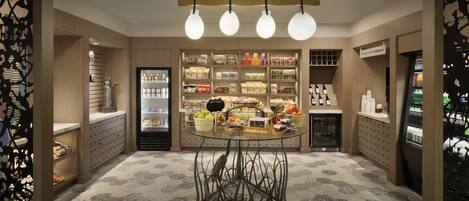 A modern interior with a central round table, shelves with various products, and a refrigerated display.