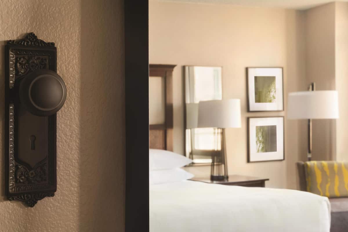 A hotel room with a bed, two bedside lamps, a nightstand, and a framed picture on the wall.