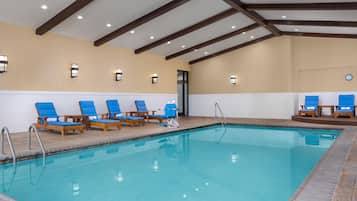 Una piscina con sillas azules y una terraza de madera.