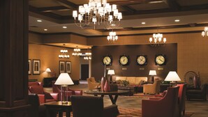 A lobby with multiple seating areas, chandeliers, clocks, and a large wheel. - DoubleTree by Hilton Cincinnati Airport (Florence)