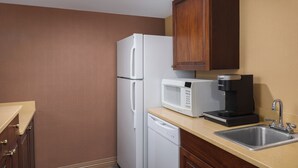 A compact kitchen with a white refrigerator, a microwave, and a coffee maker on the countertop. - DoubleTree by Hilton Cincinnati Airport (Florence)