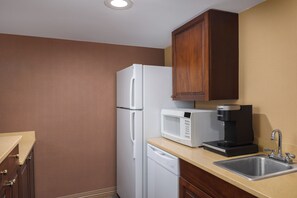 A compact kitchen with a white refrigerator, a microwave, and a coffee maker on the countertop. - DoubleTree by Hilton Cincinnati Airport (Florence)