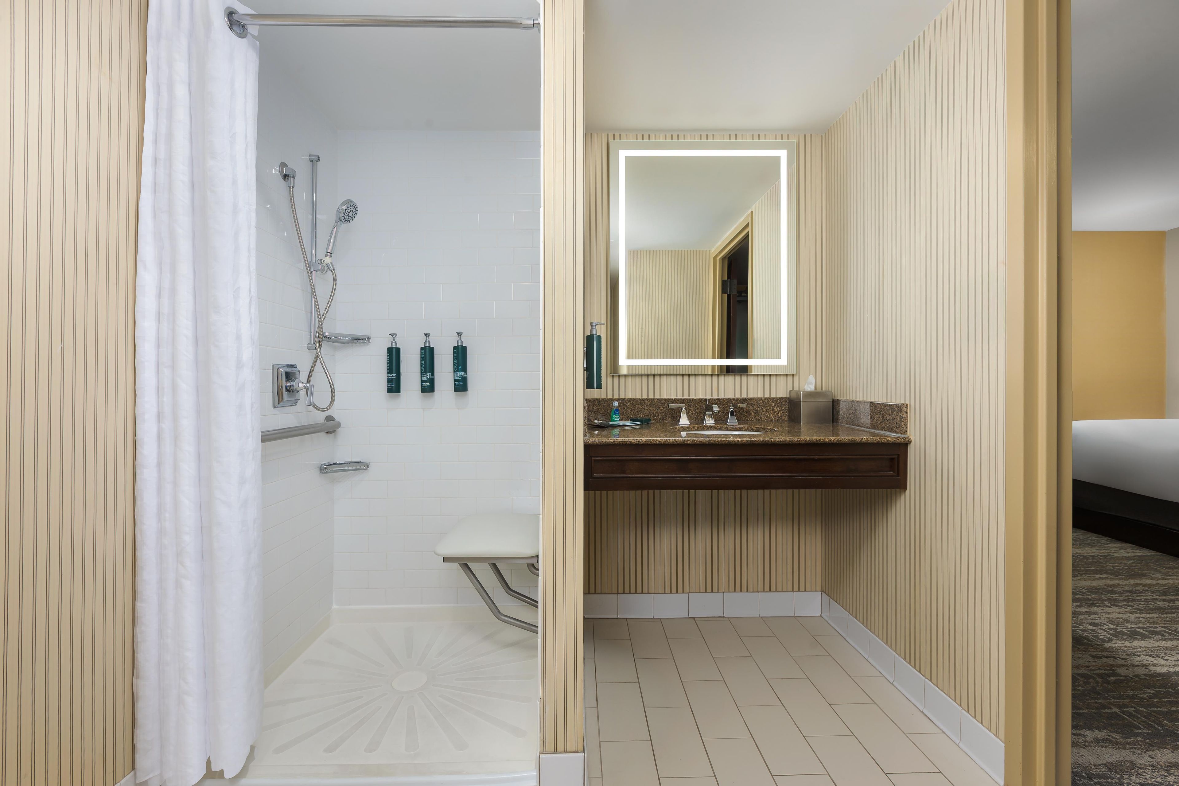 Un bagno d'albergo con doccia, WC, lavabo e specchio.