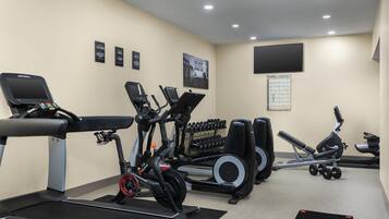 A gym with treadmills, elliptical machines, and dumbbells.