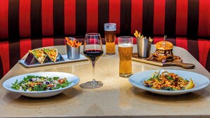 A dining table with various dishes, drinks, and a glass of red wine in a restaurant setting. - DoubleTree by Hilton Cincinnati Airport (Florence)