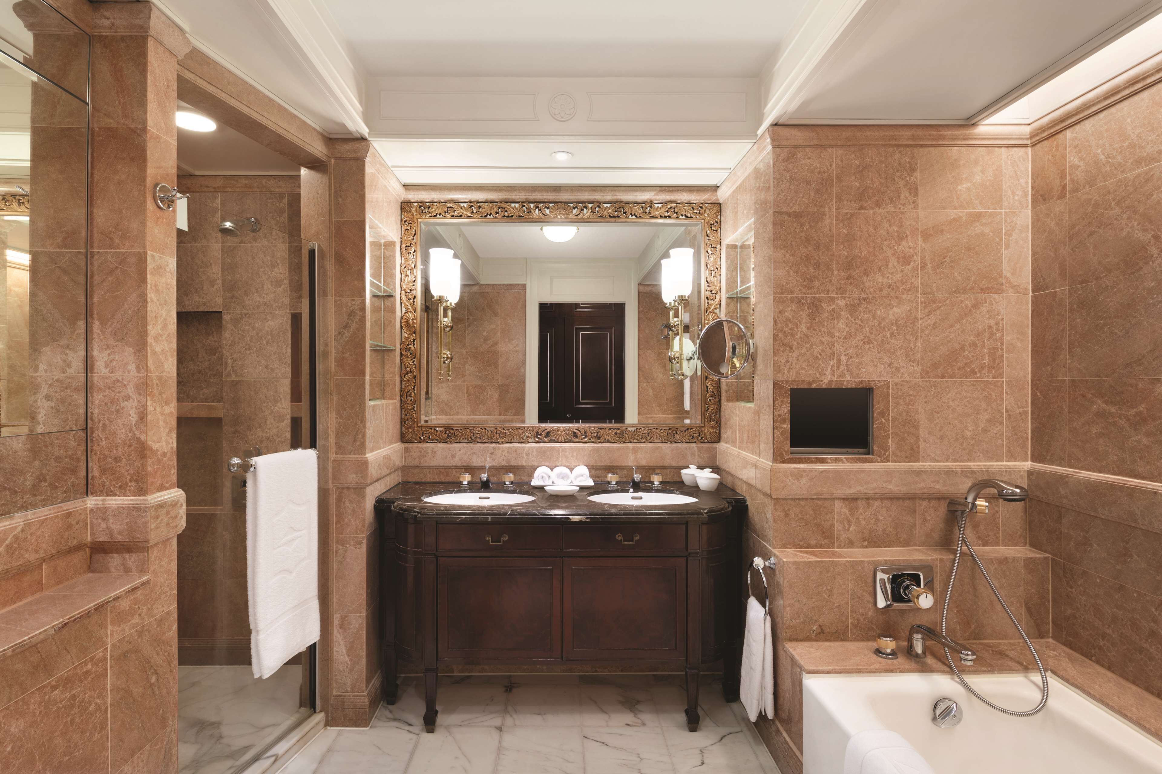 A luxurious bathroom with a double sink vanity, a large mirror, and a separate shower area.