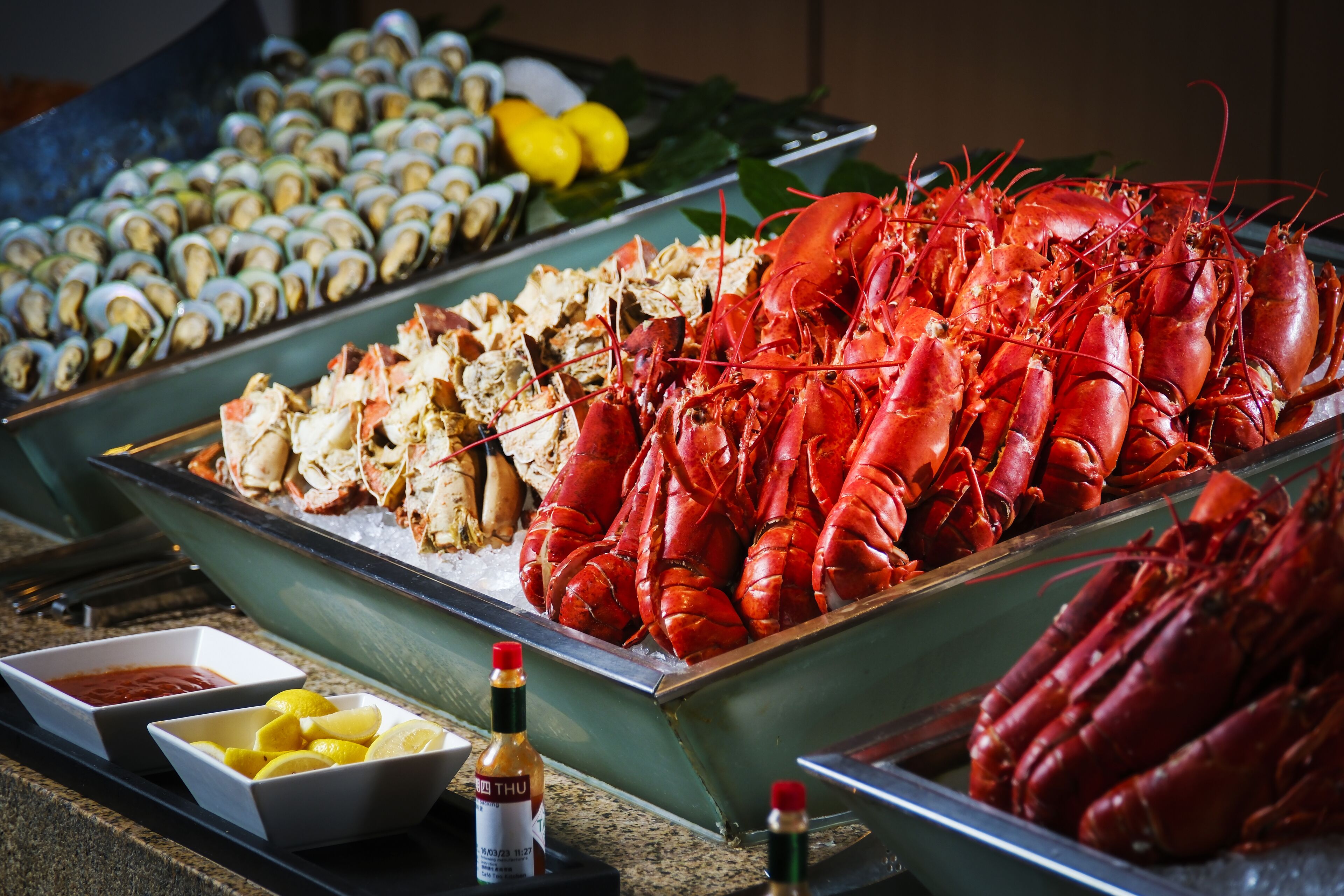 A seafood display with lobsters, oysters, and lemon wedges.