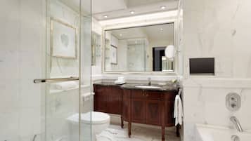 Un baño moderno con cabina de ducha de vidrio, un espejo grande, suelo de mármol y bañera empotrada.