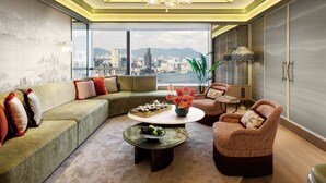 A modern living room with a large window offering a city view, a chandelier, and a mix of seating options. - Island Shangri-La, Hong Kong (Hong Kong)