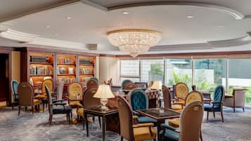 A hotel lobby with a chandelier, bookshelves, and comfortable seating.
