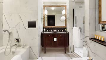 A bathroom with a marble floor, a double sink vanity, a large mirror, a bathtub, and a shower area.