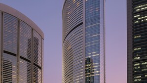 A modern skyscraper with a curved facade and illuminated signage.