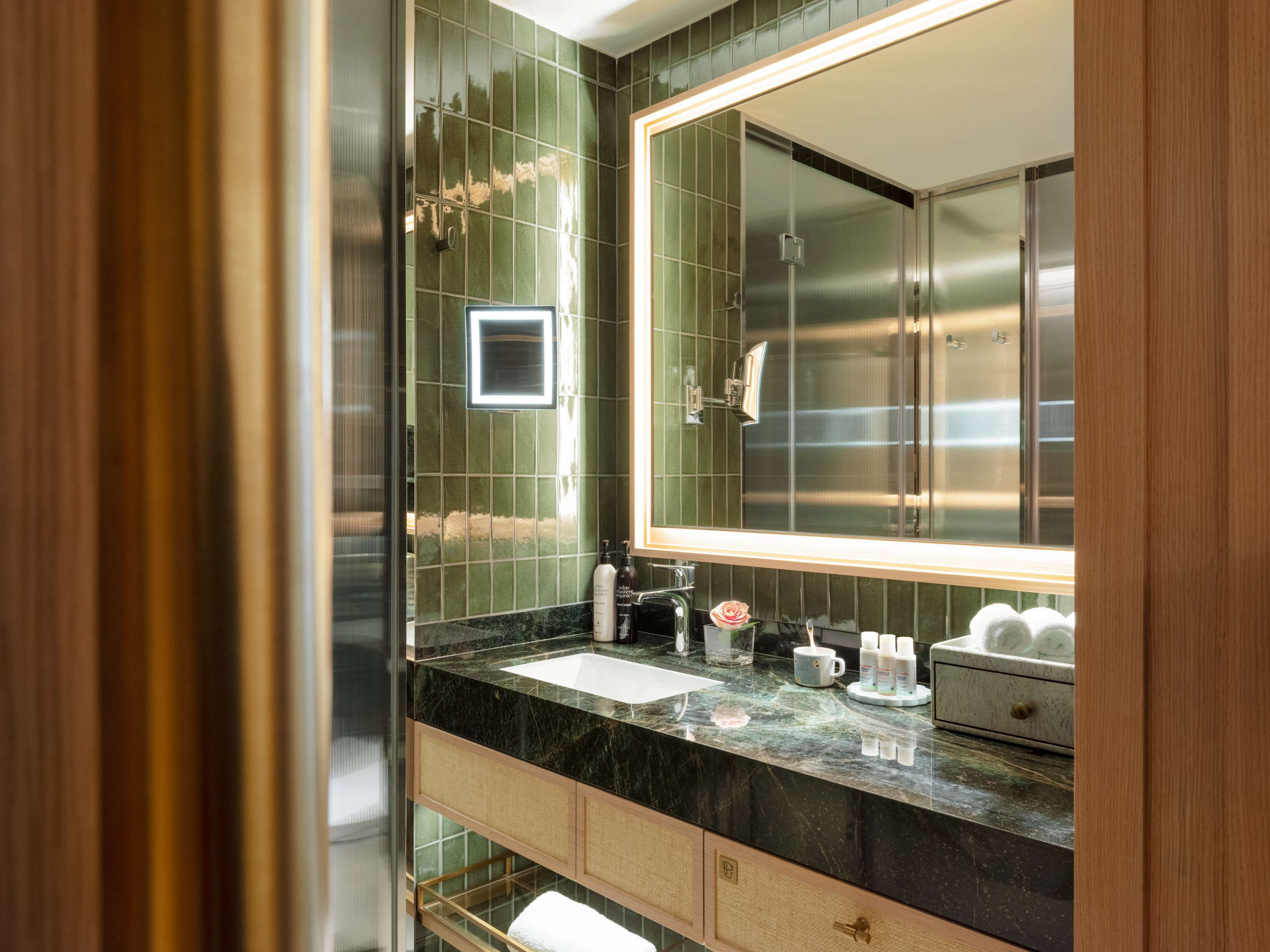 Une salle de bain moderne avec un grand miroir, un lavabo et un meuble-lavabo doté d’un porte-serviettes.