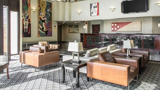 A spacious lobby with modern furniture, large abstract paintings, and a flat-screen TV mounted on the wall. - Clarion Hotel & Conference Center Ronkonkoma MacArthur Airport (Ronkonkoma)