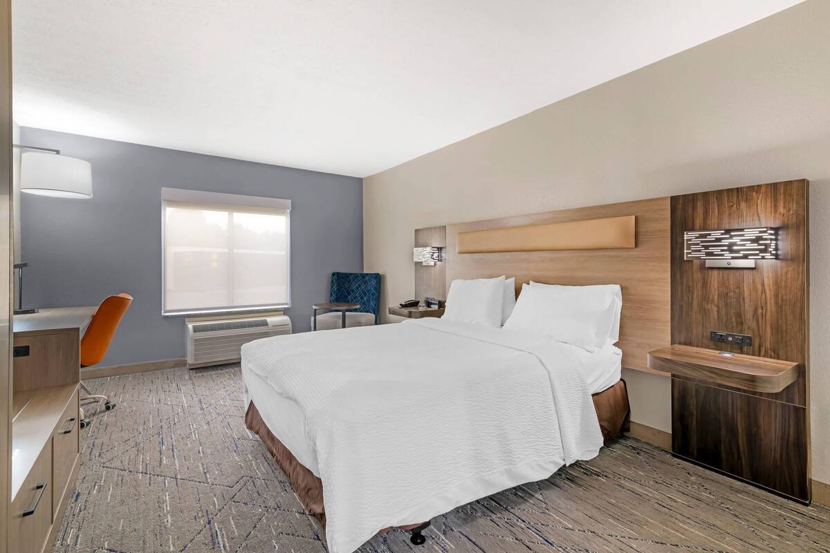 Een moderne hotelkamer met een groot bed, een bureau, een stoel en een ingebouwde kaptafel.