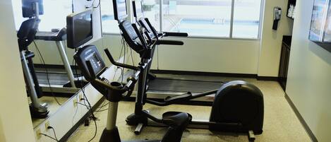 Une salle de sport équipée de machines de cardio, d’un tapis de course et d’un vélo d’appartement.