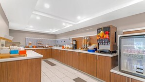 A modern kitchen with wooden cabinets, a coffee machine, a fruit juice dispenser, and a refrigerator. - Keene Elm City Hotel, an Ascend Collection Hotel (Keene)