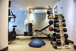 A gym with exercise equipment including a treadmill, elliptical, and a weight rack.