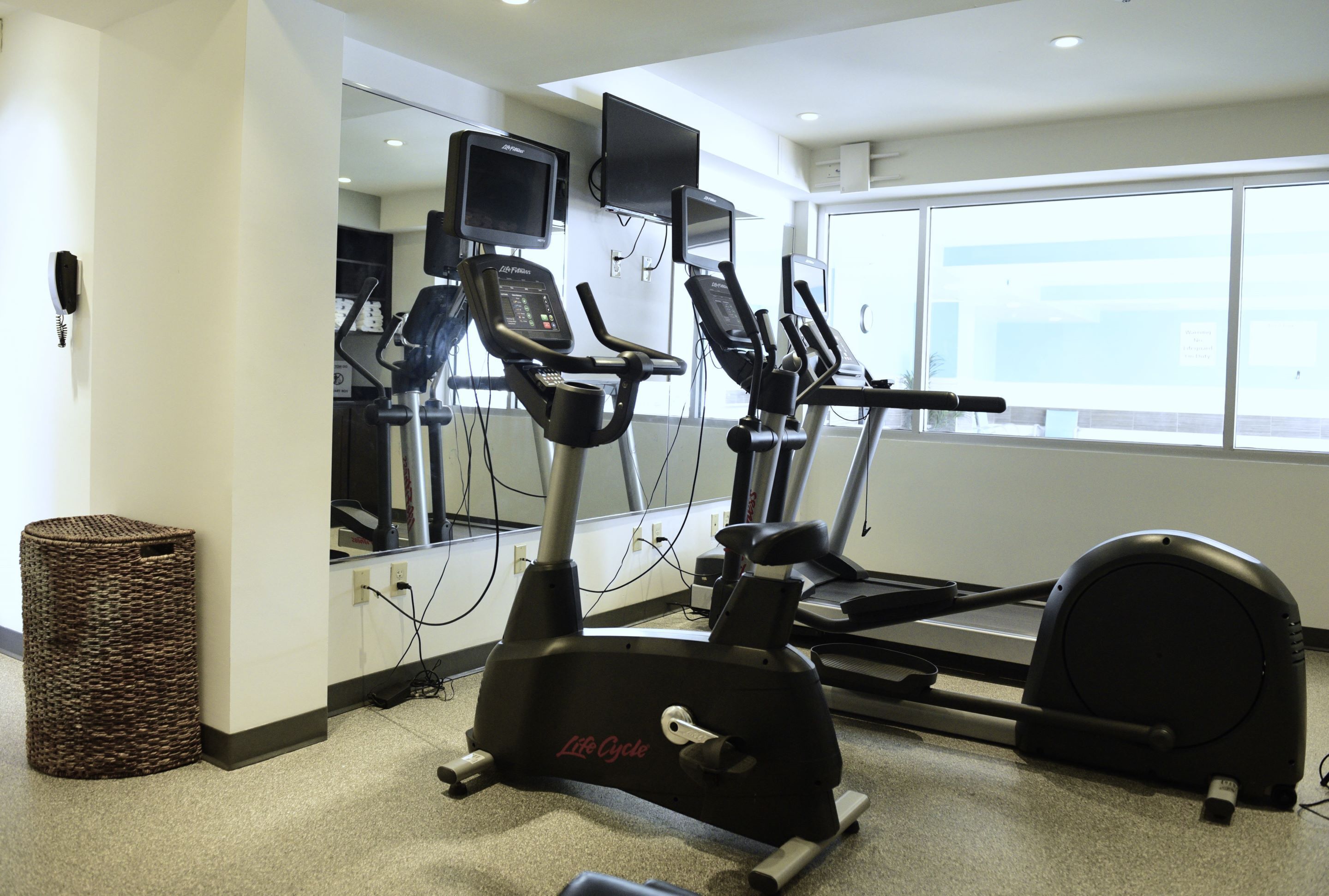 Un gimnasio con cintas de correr, una bicicleta estática y una máquina de remo.