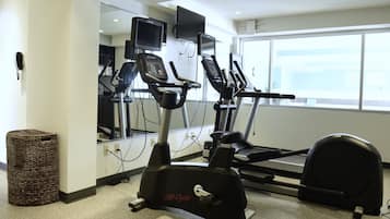 Un gimnasio con cintas de correr, una bicicleta estática y una máquina de remo.
