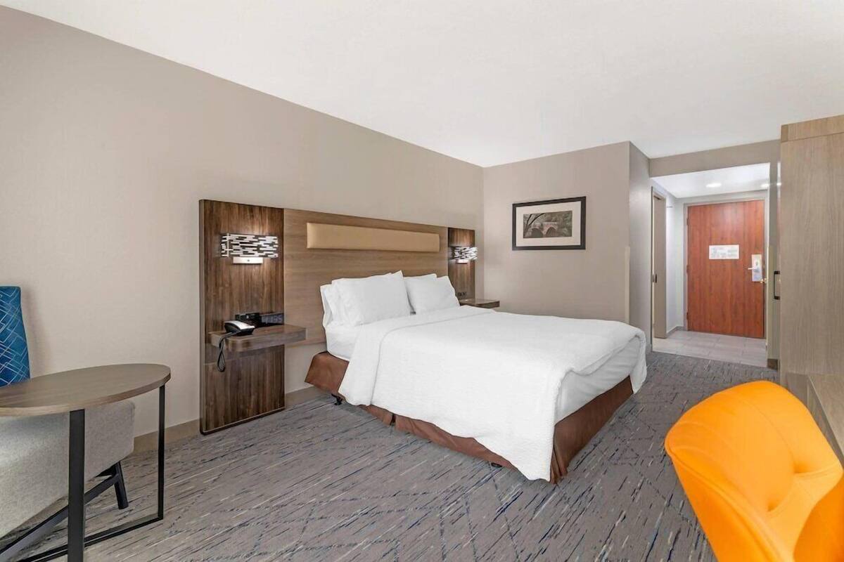 Een hotelkamer met een bed, bureau, stoel en een deur.