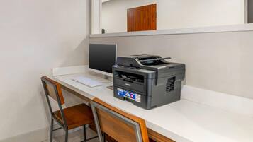 A desk with a computer, a Brother printer, and a wooden chair.