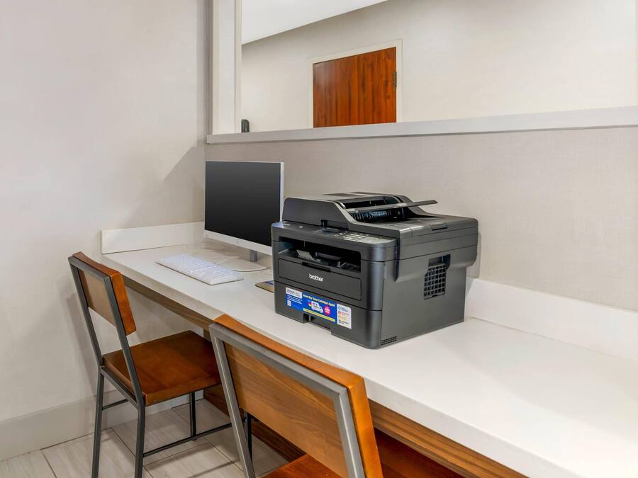 A desk with a computer, a Brother printer, and a wooden chair.