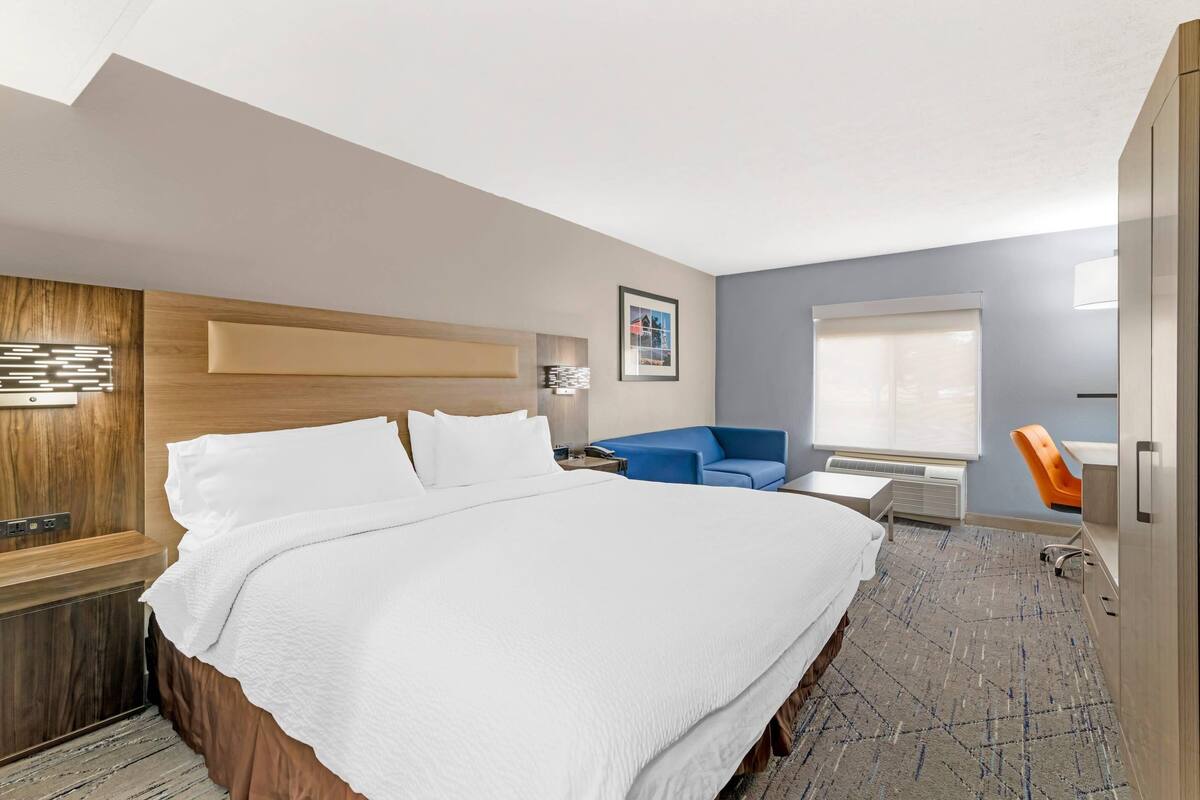 Een moderne hotelkamer met een groot bed, een bureau, een stoel en een raam.