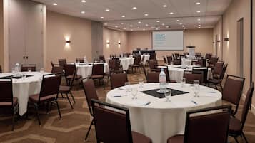 A conference room with multiple round tables, each set with chairs, water bottles, and glasses.