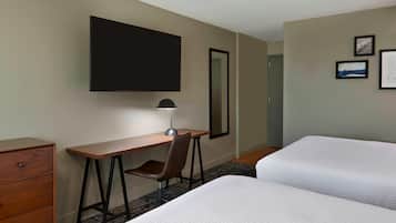 Habitación de hotel con cama, escritorio, silla, televisor de pantalla plana y puerta.