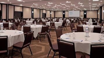 A conference room with multiple round tables, each set with chairs, water bottles, and glasses.