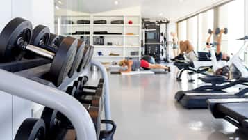Une salle de sport équipée de divers appareils d’exercice, notamment des haltères, des tapis de course et des appareils de musculation.