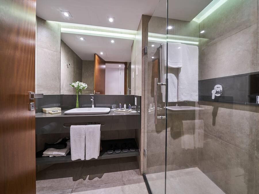 Un baño moderno con ducha de vidrio, tocador con lavamanos y espejo.