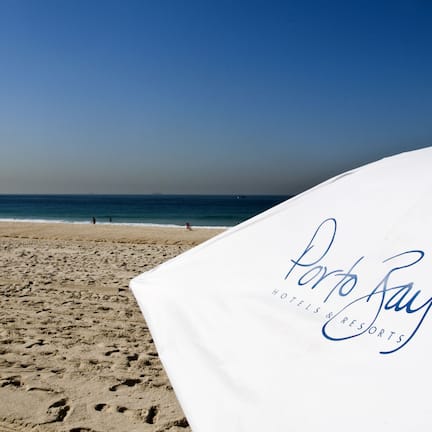 Na praia, areia branca, espreguiçadeiras, toalhas de praia