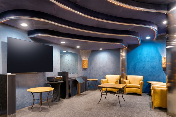 A modern home theater room with curved ceiling design, a large flat-screen TV, and comfortable seating.