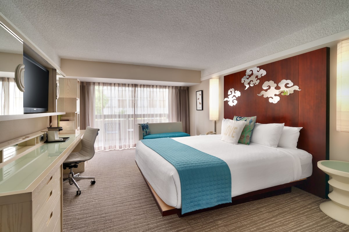 A hotel room with a bed, a desk, a chair, a television, and a bathroom.