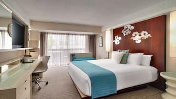 A hotel room with a bed, a desk, a chair, a television, and a bathroom.