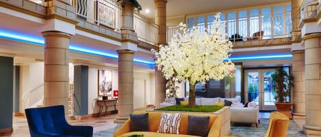 A spacious lobby with a high ceiling, a large skylight, and a central seating area with sofas and a coffee table.
