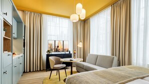Una habitación de hotel moderna con cama, sofá, mesa de comedor y escritorio con silla.