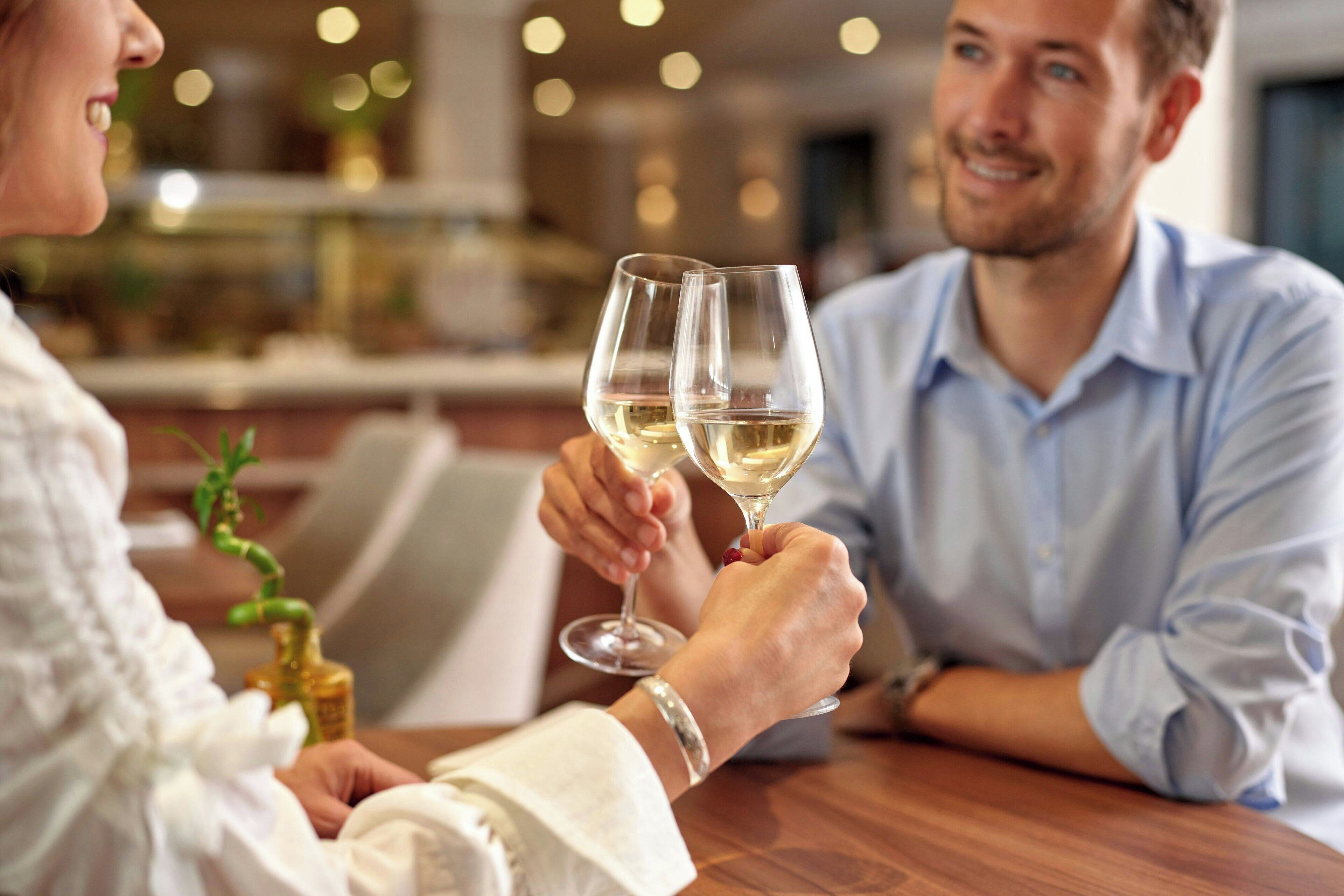 Una pareja brindando con copas de champán en una mesa de madera en un ambiente interior bien iluminado.