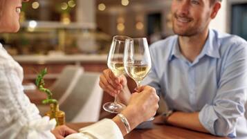 Una pareja brindando con copas de champán en una mesa de madera en un ambiente interior bien iluminado.