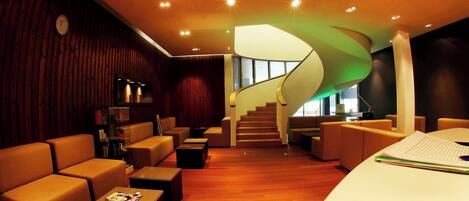 A modern interior with a curved staircase, leather seating, and a wooden floor.