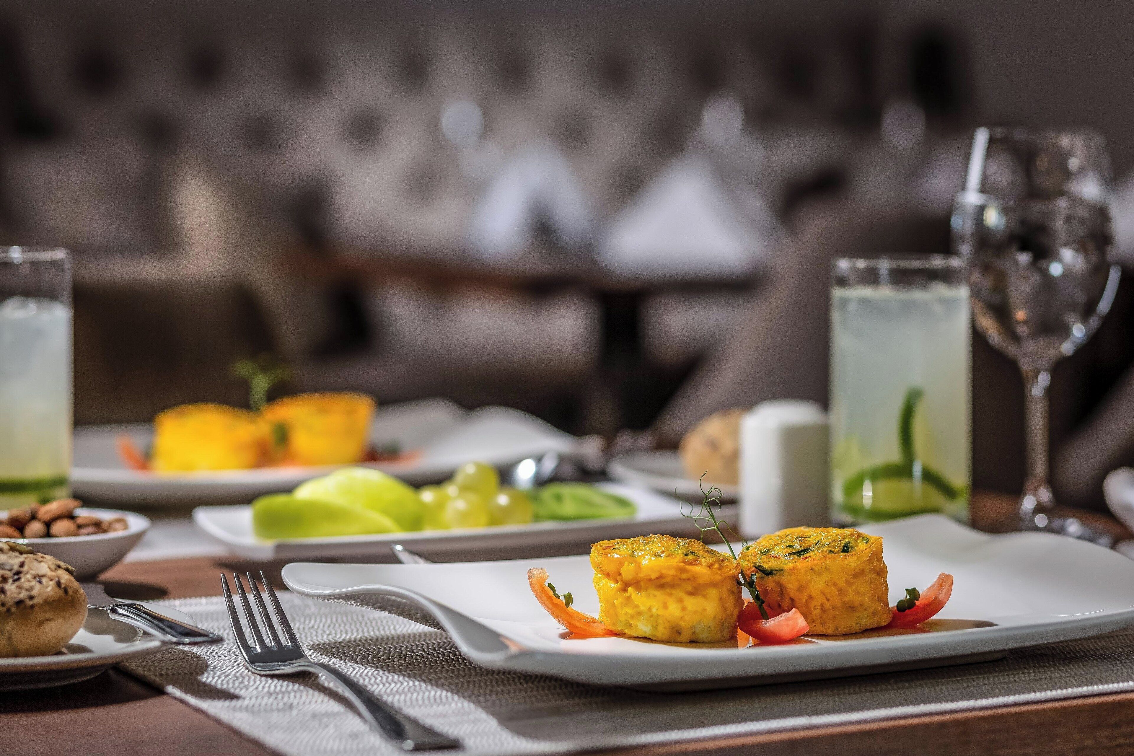 A dining table with a plate of food, a glass of water, and a fork.