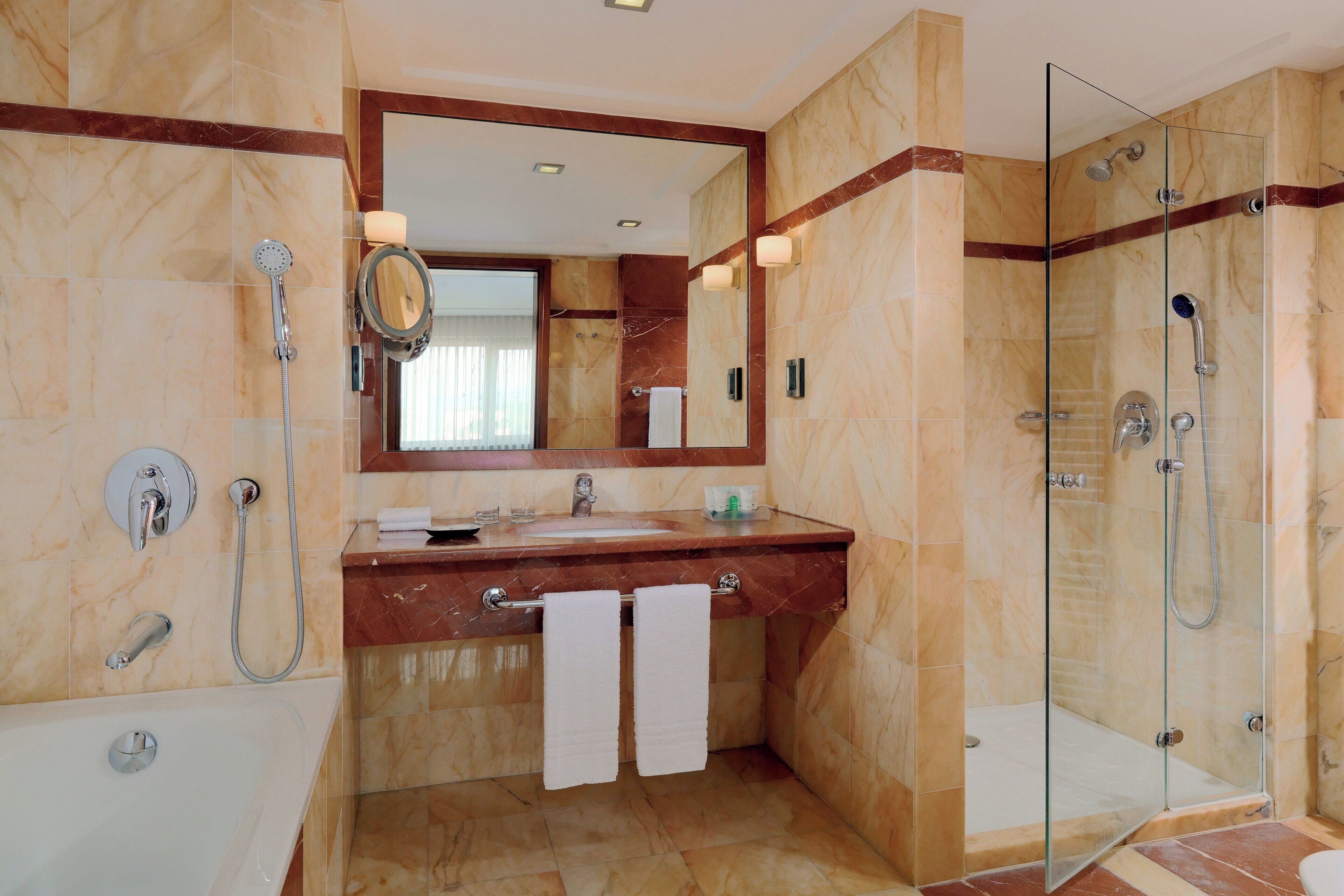 Une salle de bain moderne avec une douche à parois de verre, un meuble-lavabo en marbre et un grand miroir.